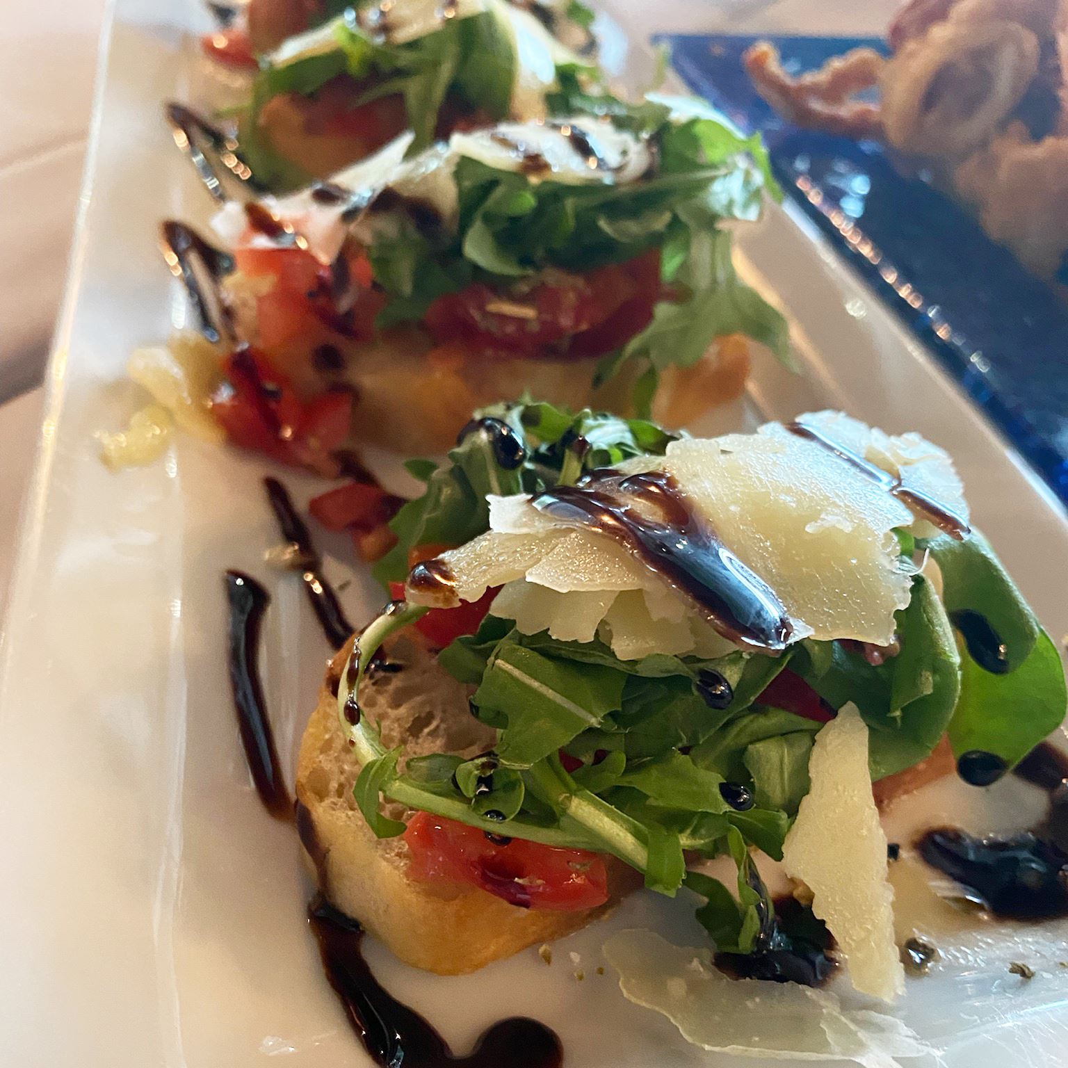 Bruschetta on bread topped with lettuce and parmesan