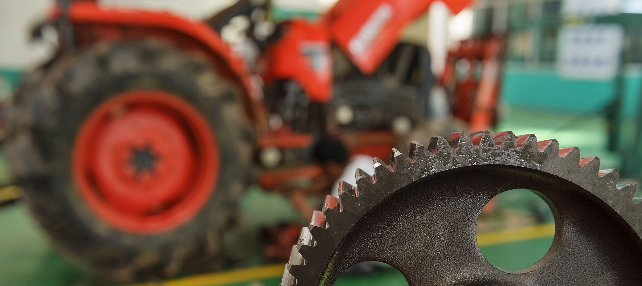 Close up of a gear with an out of focus tractor in the background