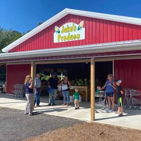 Large red barn with produce inside with a sign that reads "Jake's Produce"