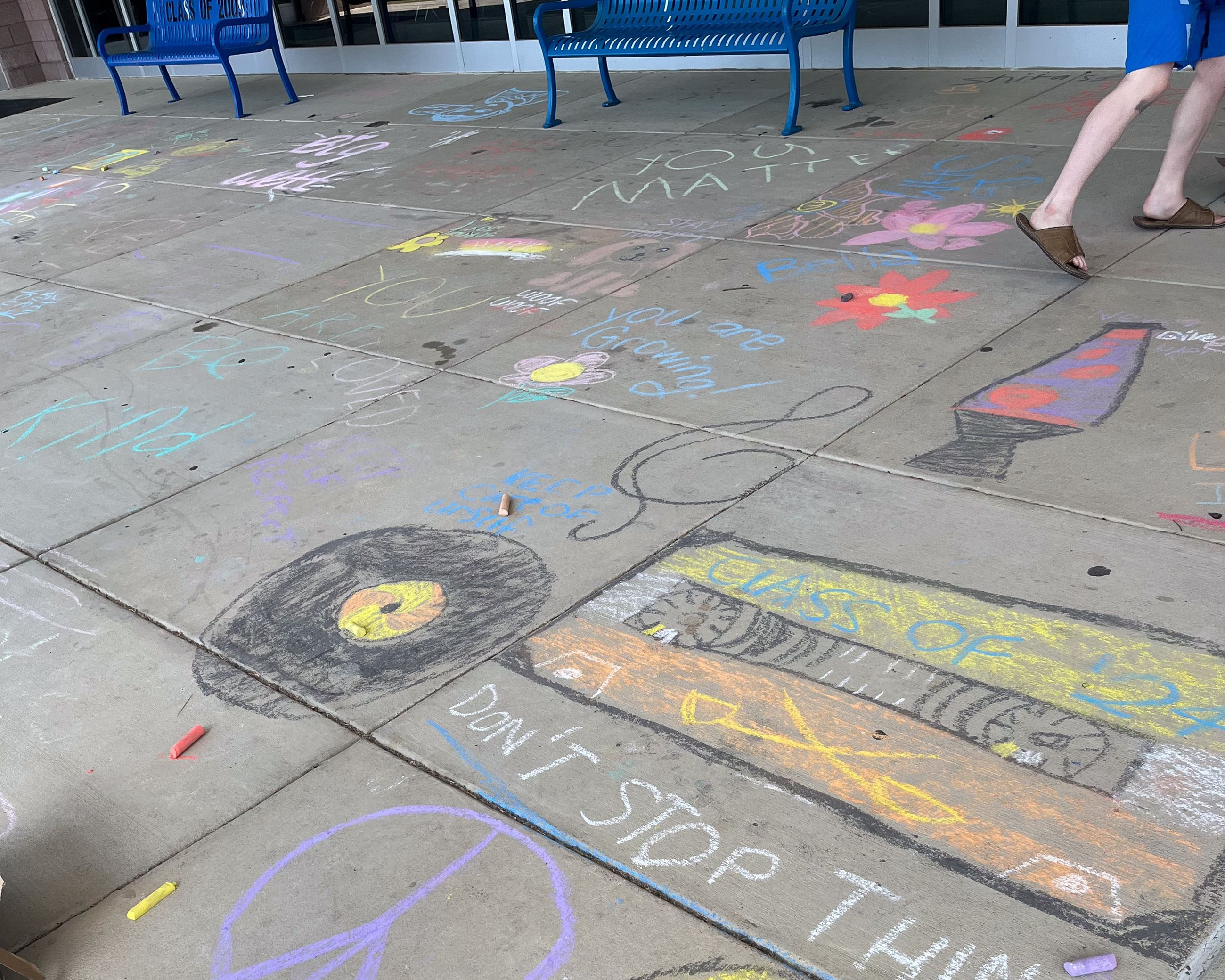 Multicolored sidewalk chalk art with text "Reminder! Pass on kindness."